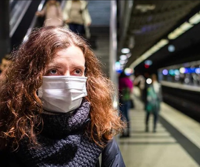 close up of women on train platform wearing a medical face mask