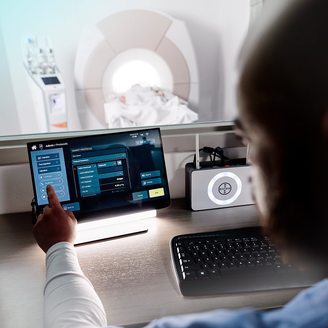 Radiology control room with touchscreen interface monitoring a patient in CT scanner